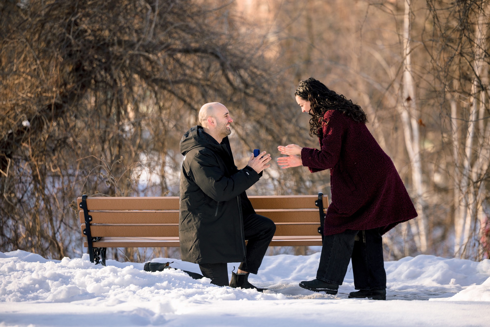 Congress Park proposal in Saratoga Springs NY with couple celebrating engagement on a sunny winter day